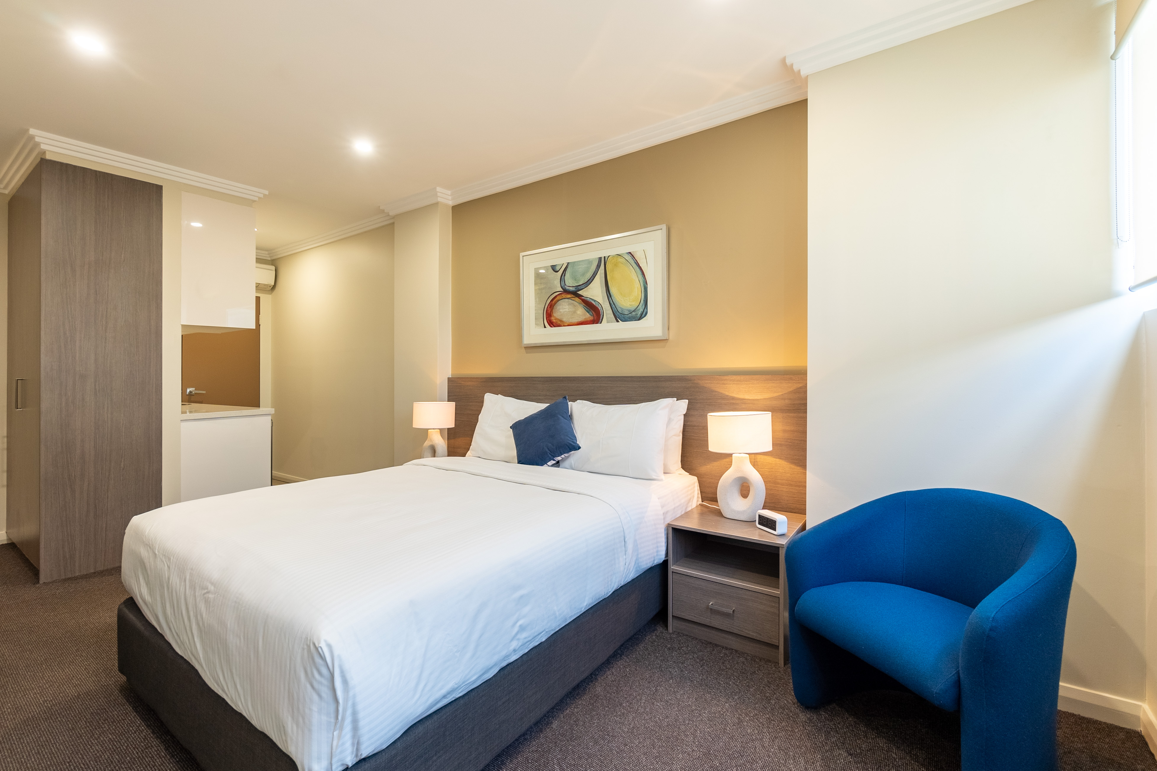 Blue chair and queen bed at BW Plus Camperdown Suites Sydney